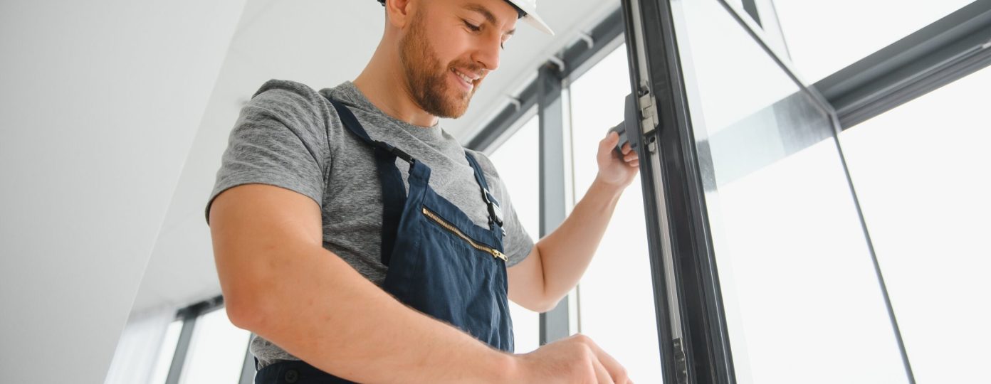 Construction worker repairing plastic window with screwdriver indoors, space for text. Banner design